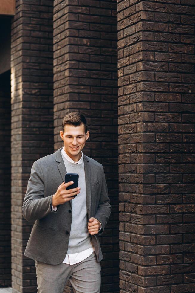 Modern handsome smiling man walking down the street and talking on the phone photo