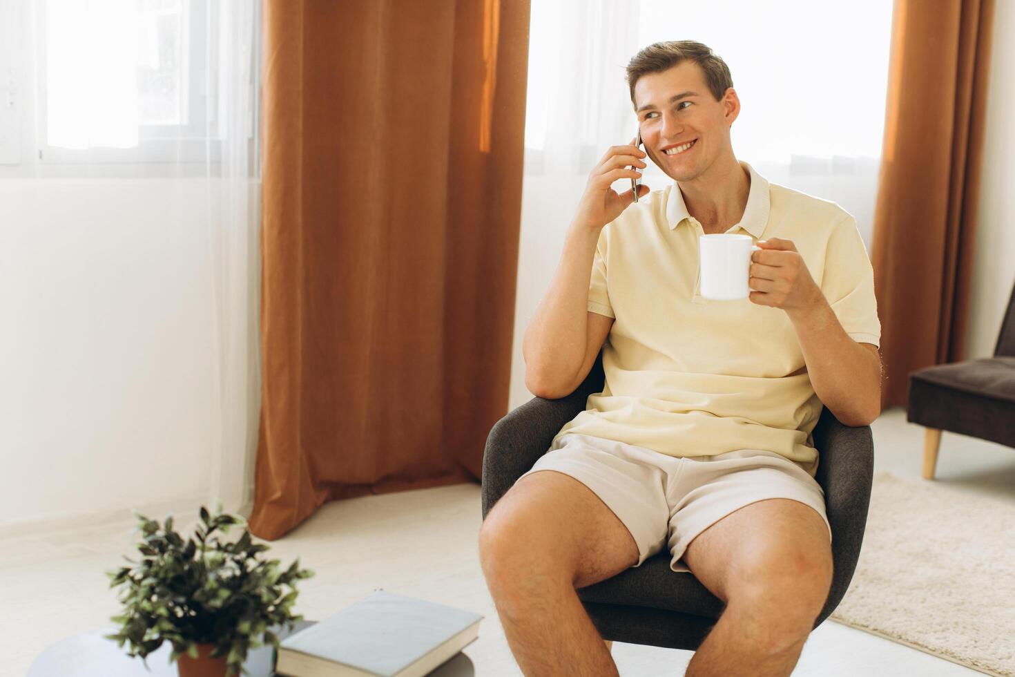 A handsome guy in yellow casual clothes is sitting at home and talking on the phone photo