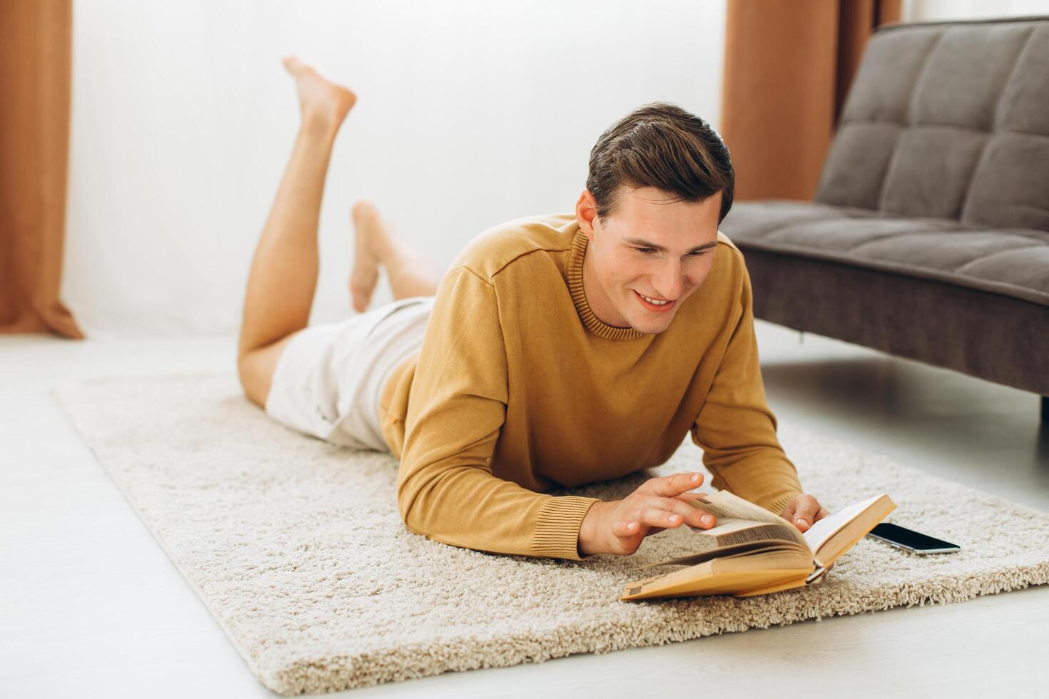 Handsome young man in yellow casual clothes sitting at home reading a book photo