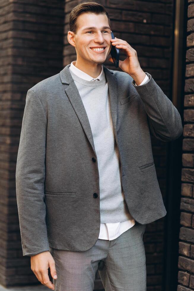 Modern handsome smiling man walking down the street and talking on the phone photo