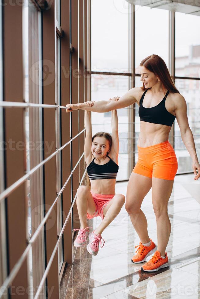 The daughter holds on to the mother's strong hand in the gym during training photo