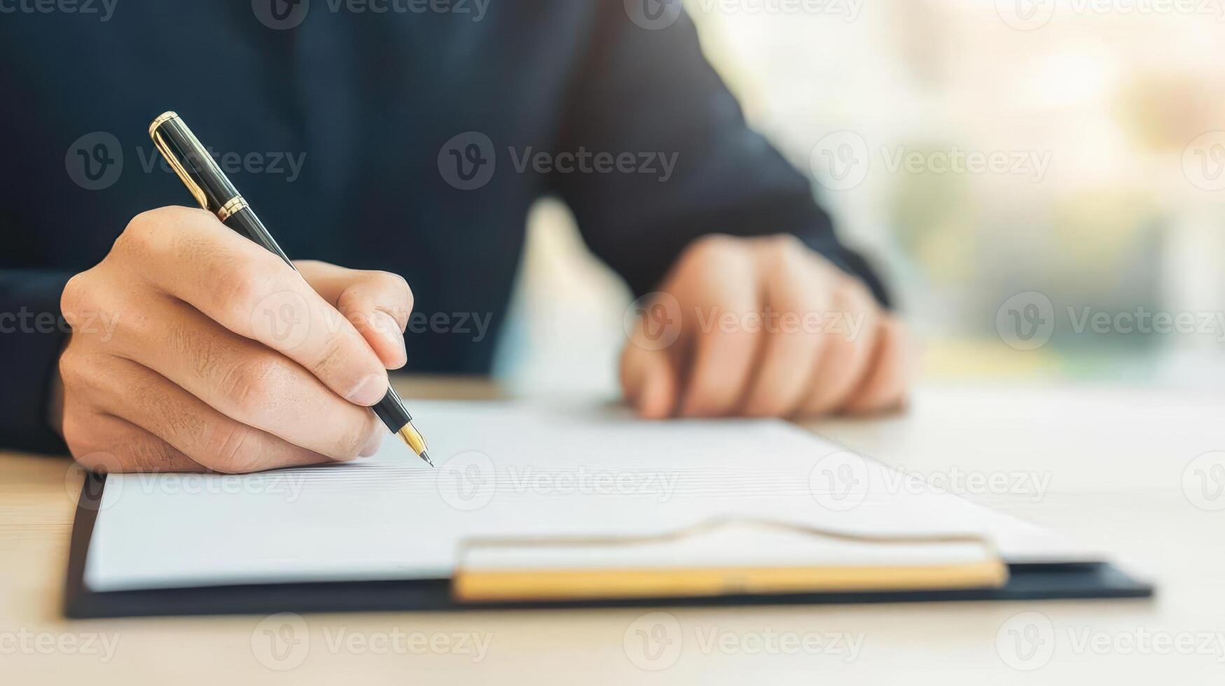 A focused businessman takes notes at his home office desk, capturing essential details for effective planning and strategy. photo