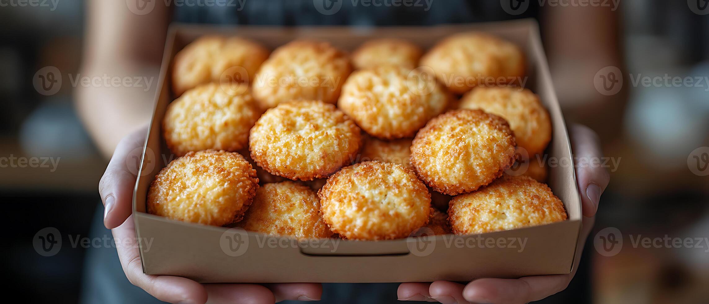 A person holding a box of freshly baked golden cookies. photo