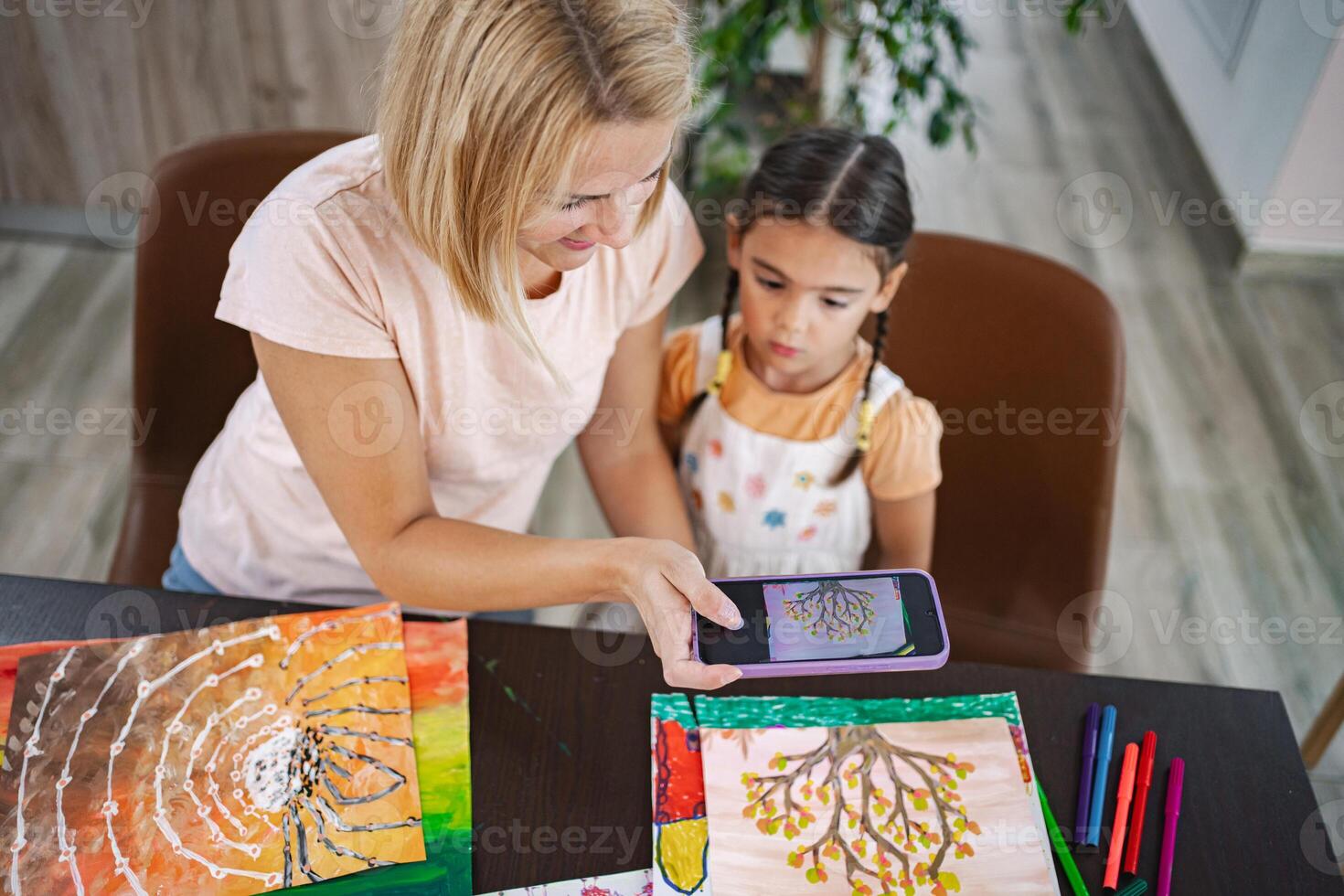 Mother and daughter take pictures of artwork with mobile camera photo