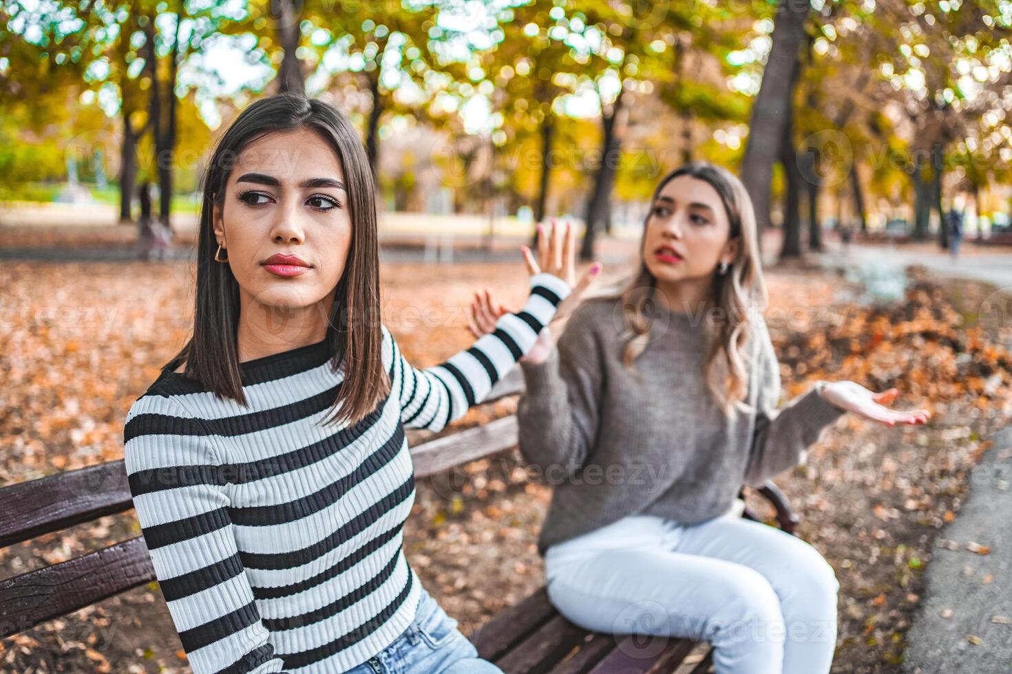 Two women are sitting on a bench and one does not want to listen to the other anymore photo