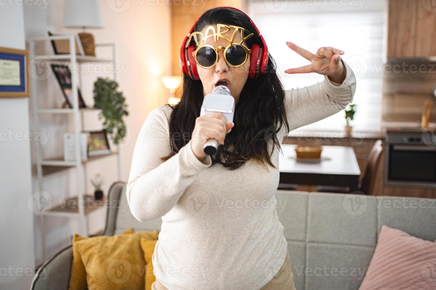Woman with wireless headphones singing karaoke at home photo