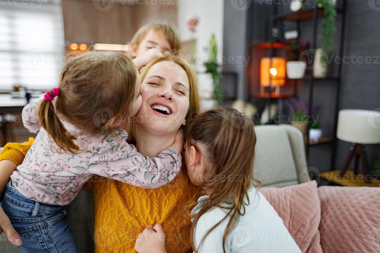 Three cute little girls hug, kiss and play with their mom photo