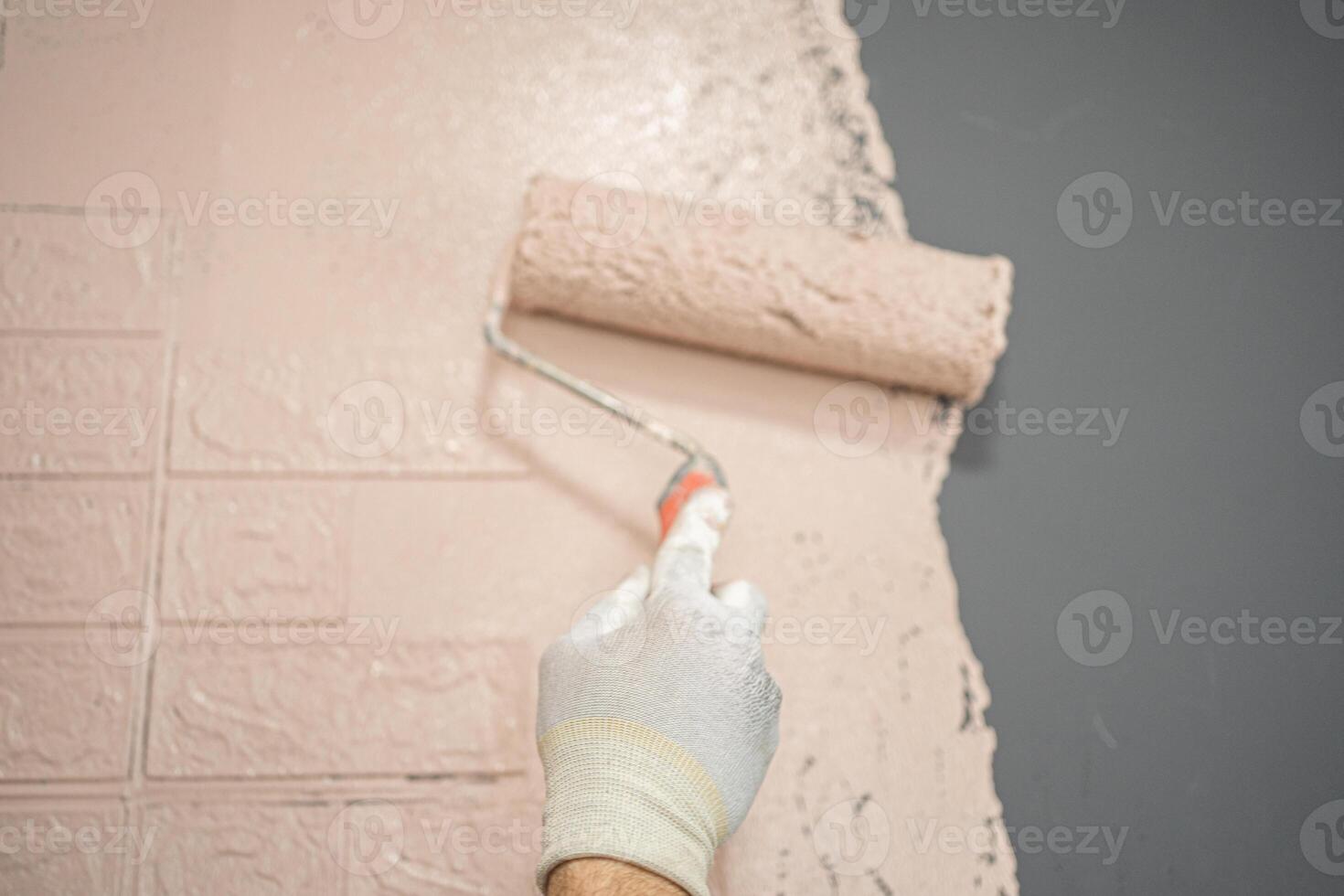 Person Painting a Brick Wall With a Paint Roller photo