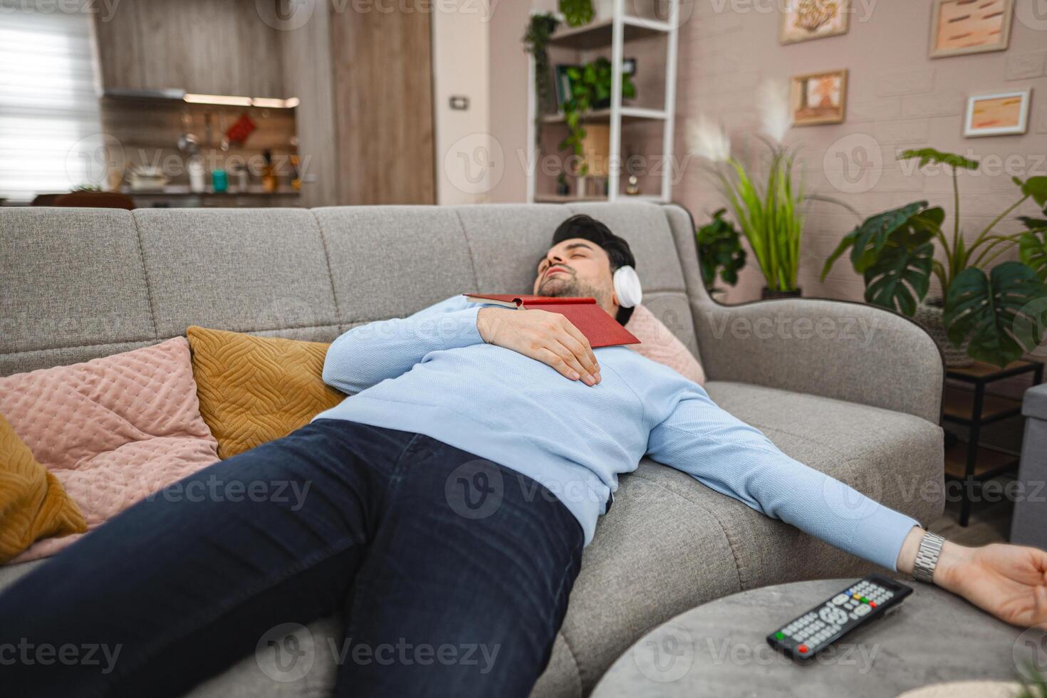 Man with wireless headphones fell asleep while reading a book at home photo