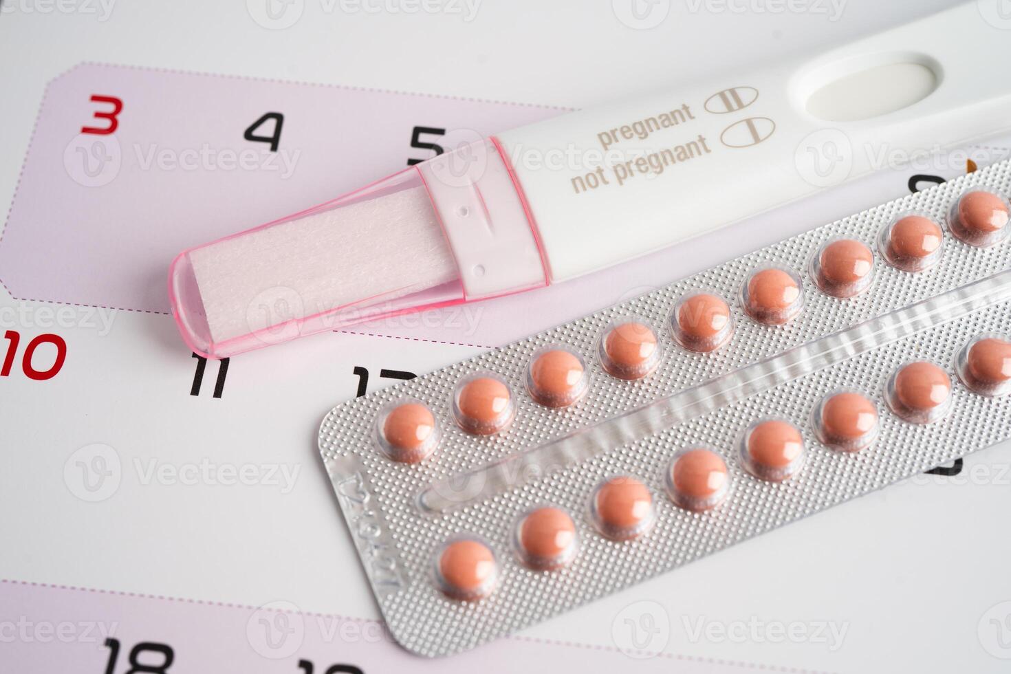 Pregnancy test and birth control pills on calendar, contraception health and medicine. photo