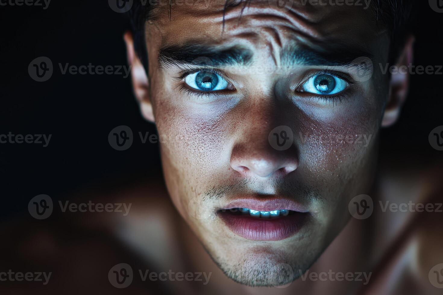 Portrait of an athletic man with striking blue eyes in low light photo