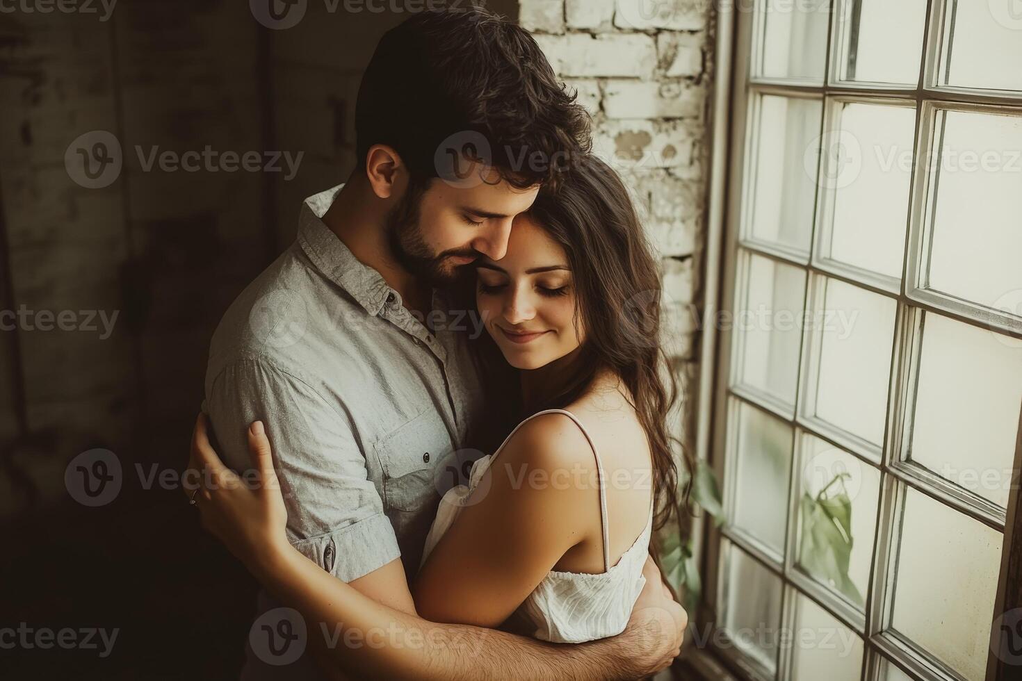 Couple embraces inside a rustic room with natural light at sunset photo