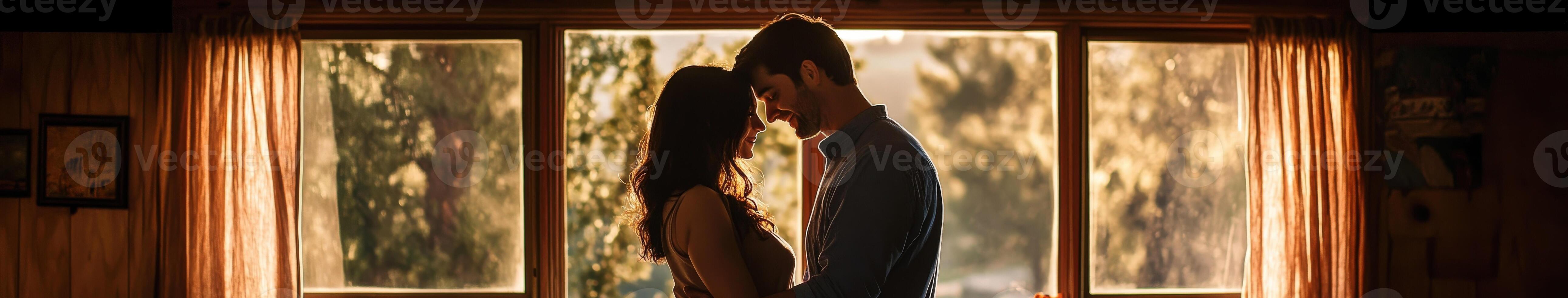 Couple embraces warmly by the window at sunset in a cozy cabin photo