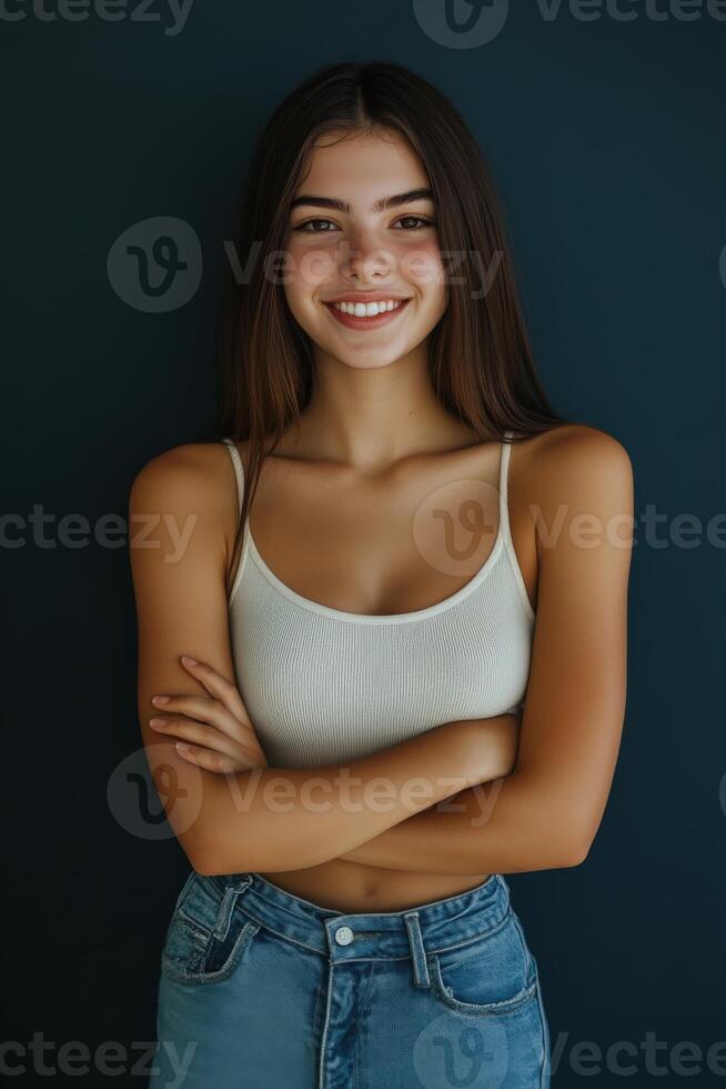 Young woman poses confidently with crossed arms against a dark background photo