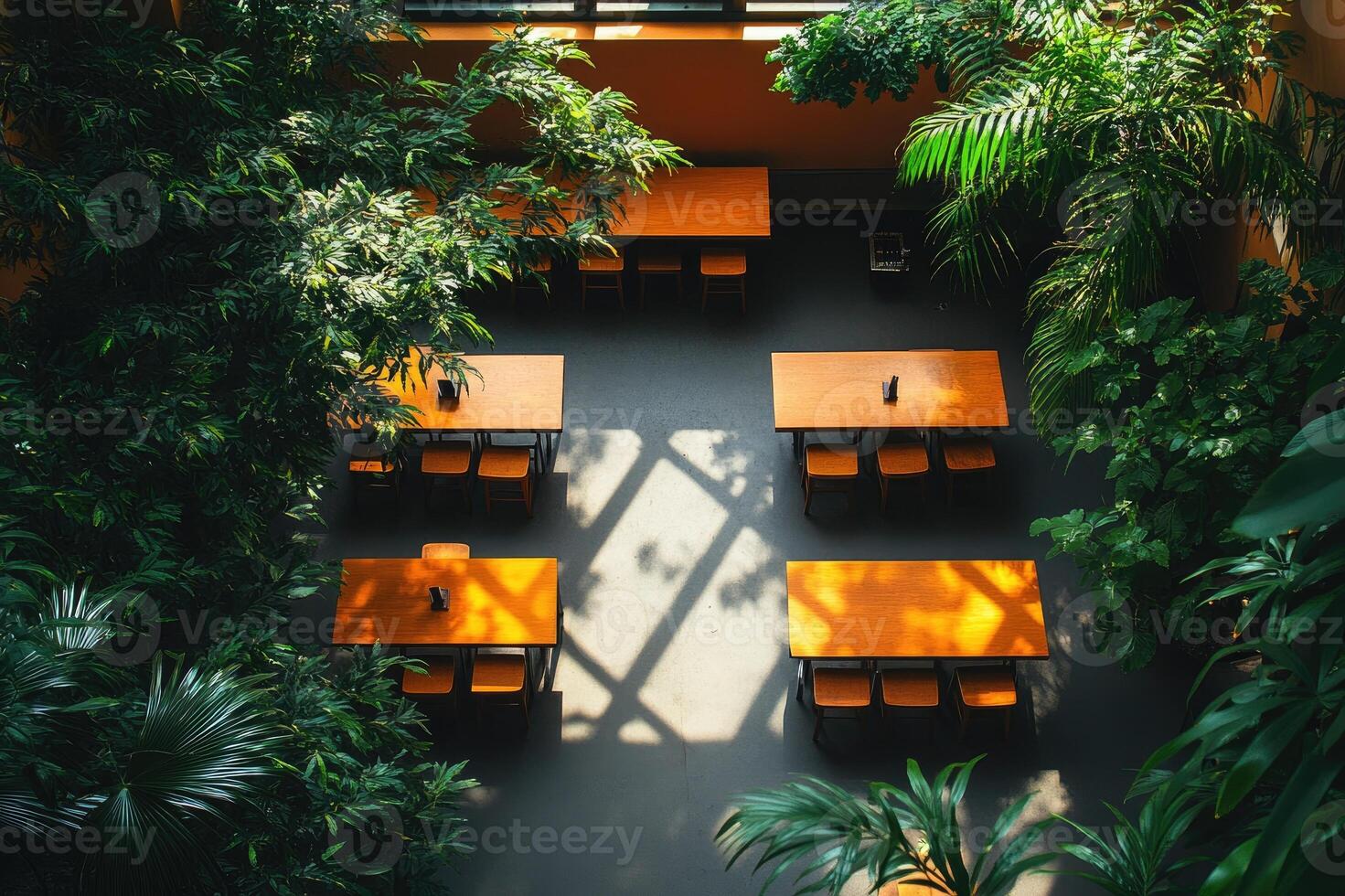 Sunlight illuminating tables in empty restaurant surrounded by lush greenery photo