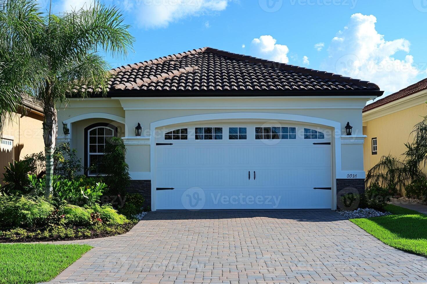 New one-story home with a tile roof and a brick paver driveway photo