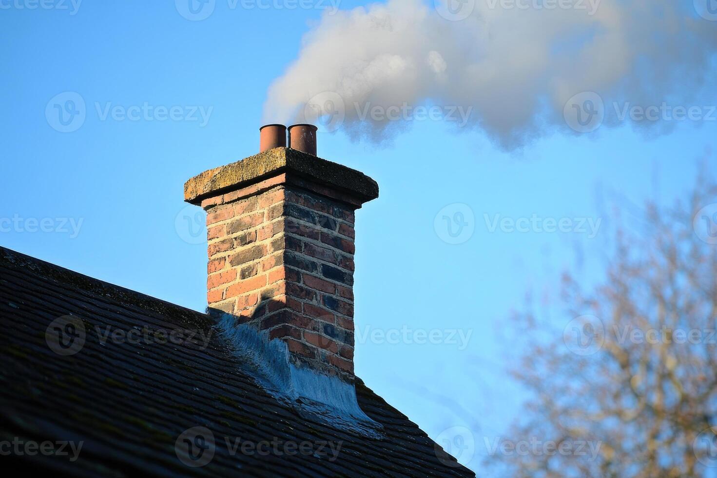 Brick chimney releasing white smoke into blue sky photo