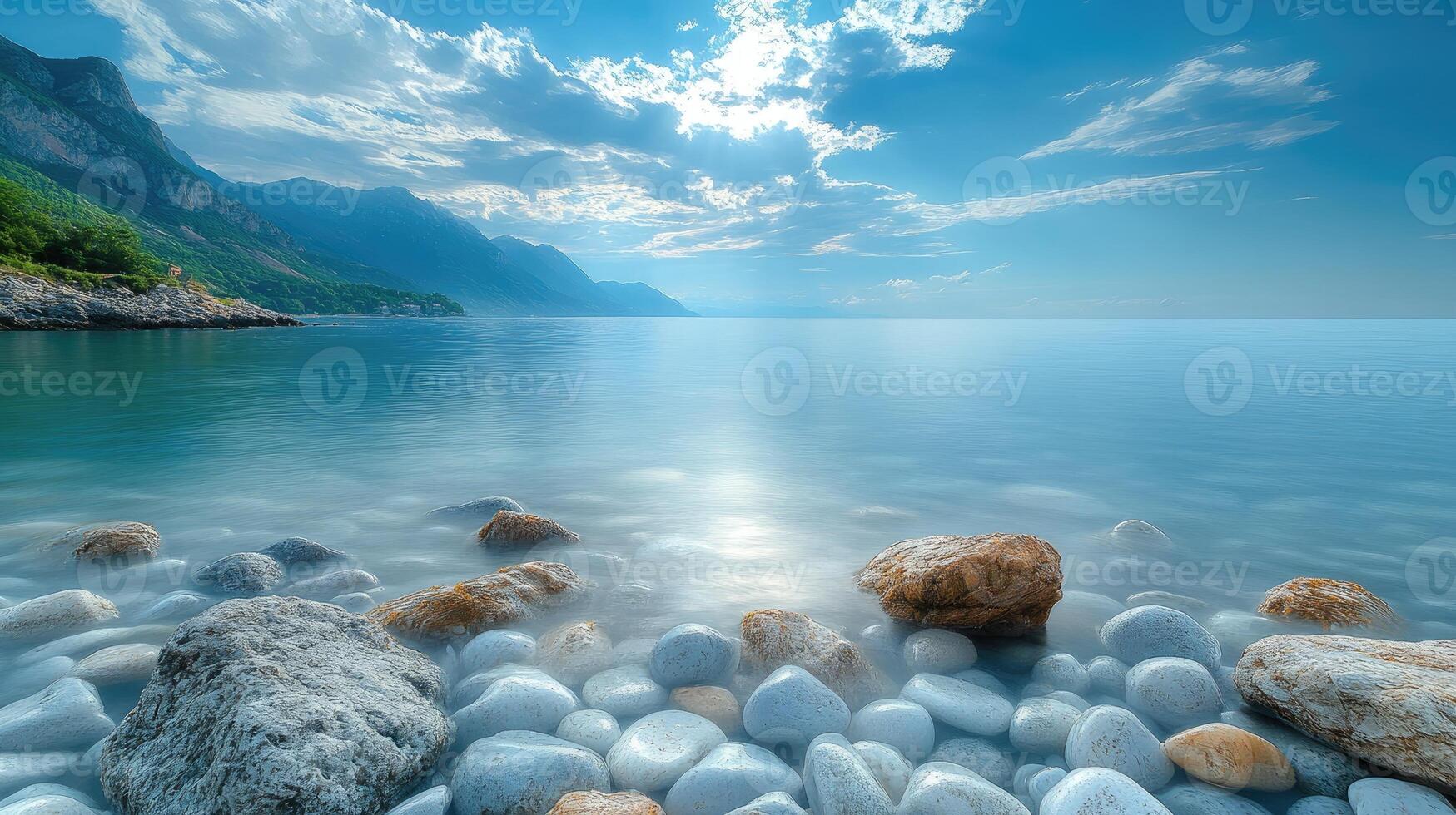 Tranquil sea with white pebbles on the beach and mountains in the distance photo