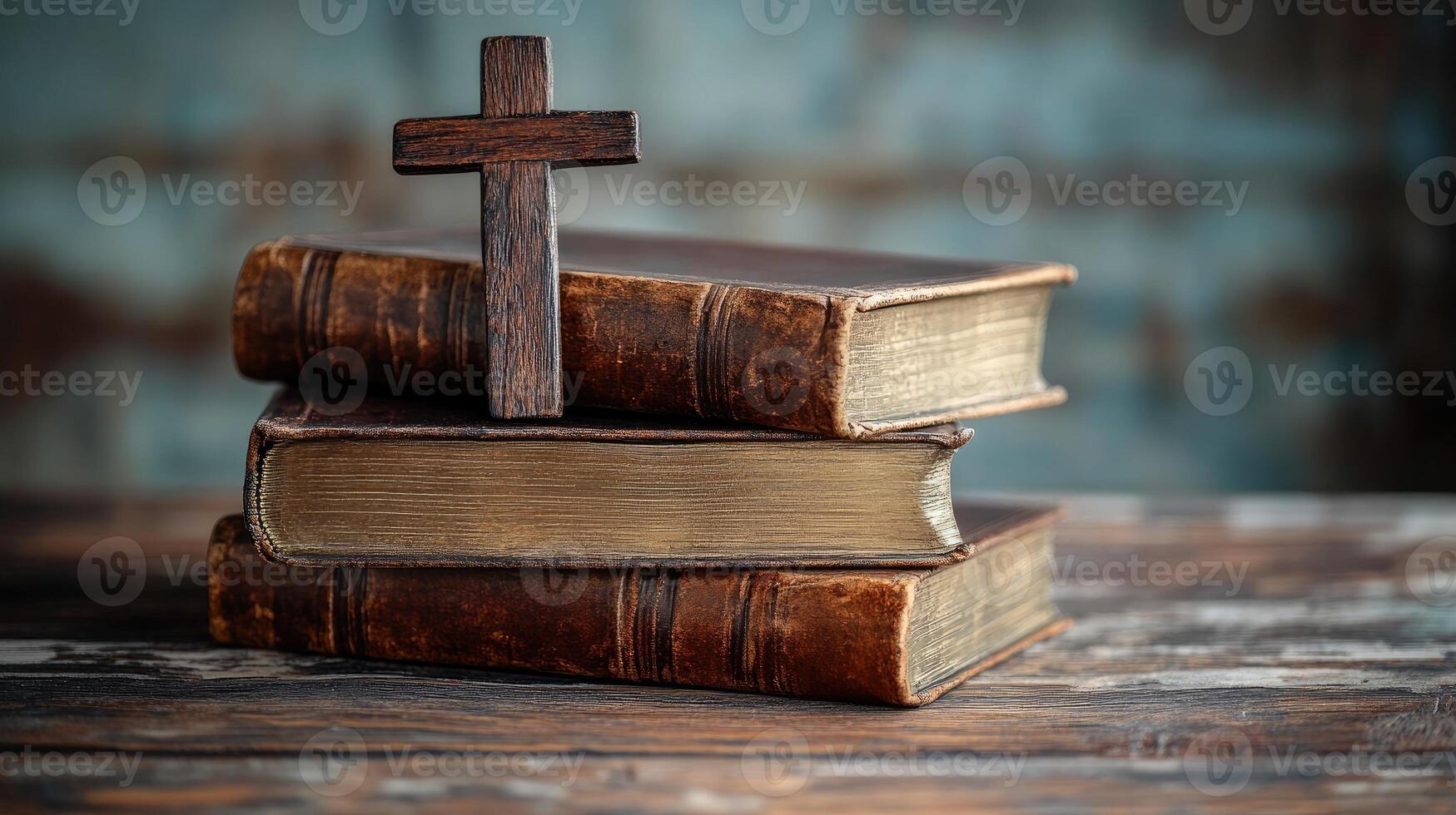 Wooden cross resting on stack of old books on desk photo