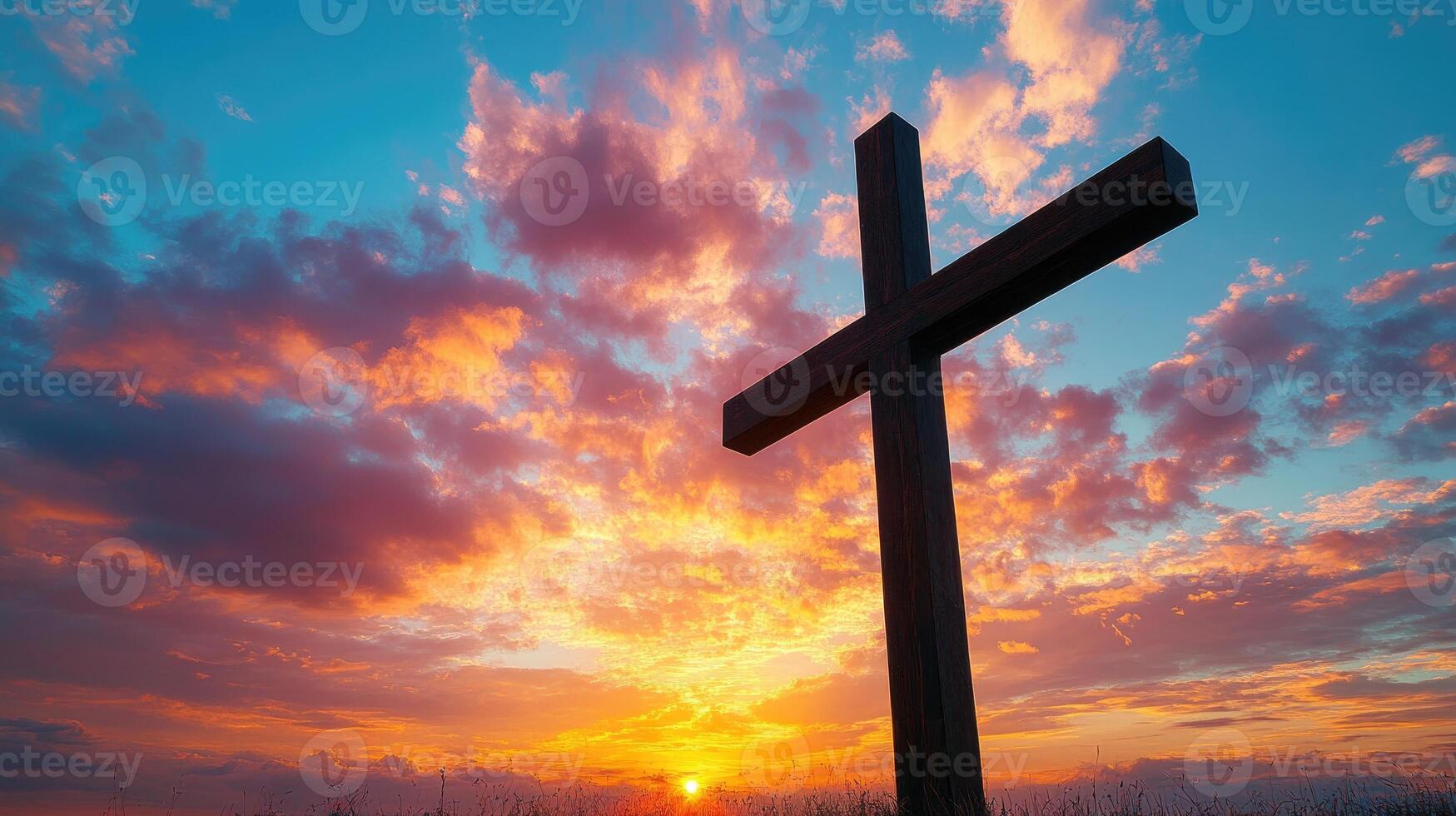 Large wooden cross standing in field at sunset with vivid clouds photo