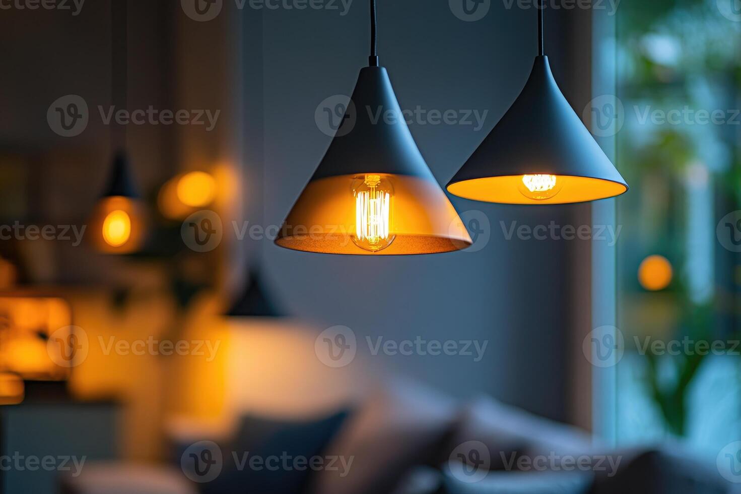 Modern ceiling lamps hanging and illuminating living room with cozy blurred background photo