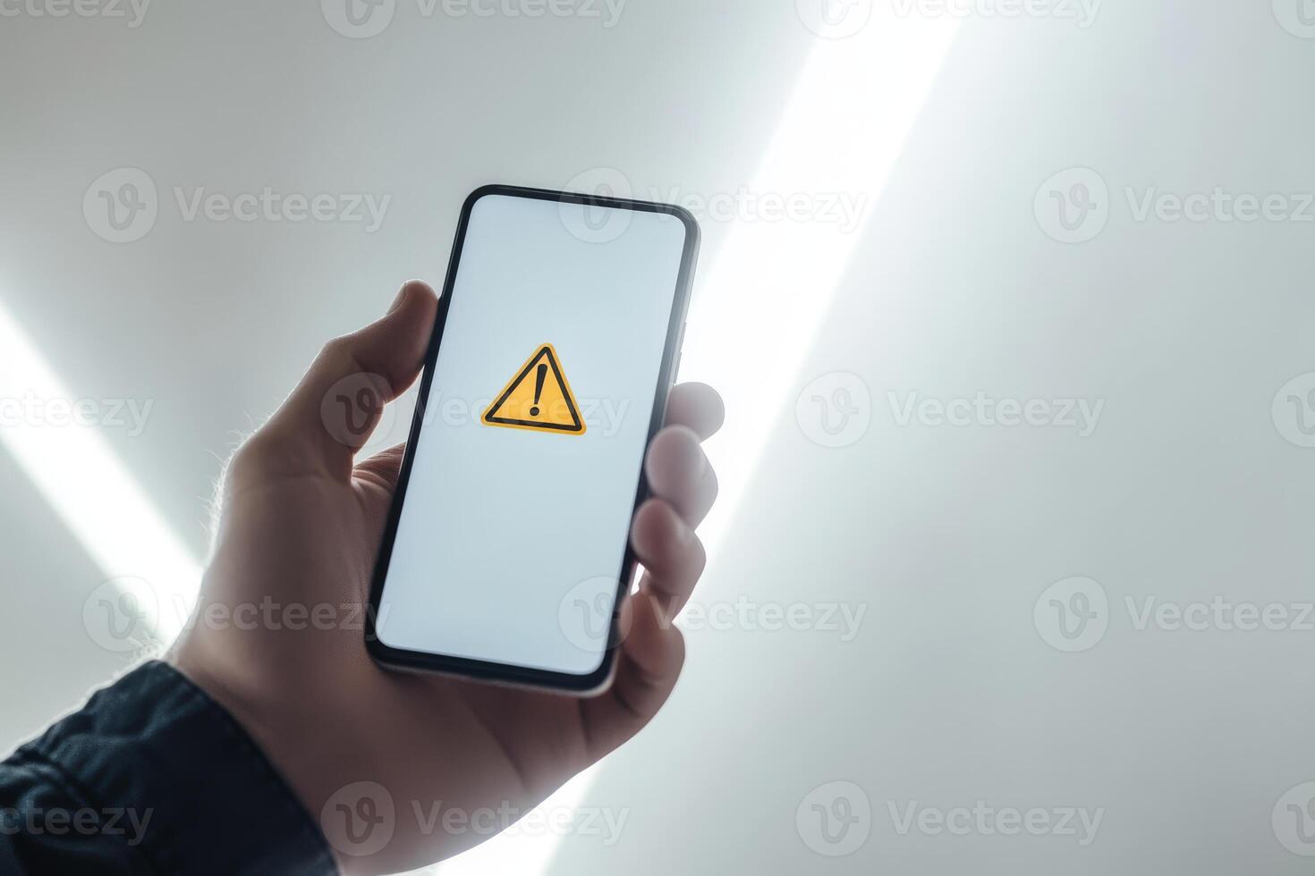 A hand grips a smartphone showing a warning sign, highlighting the importance of caution in financial decisions, investments, and awareness of potential economic risks that could cause harm photo