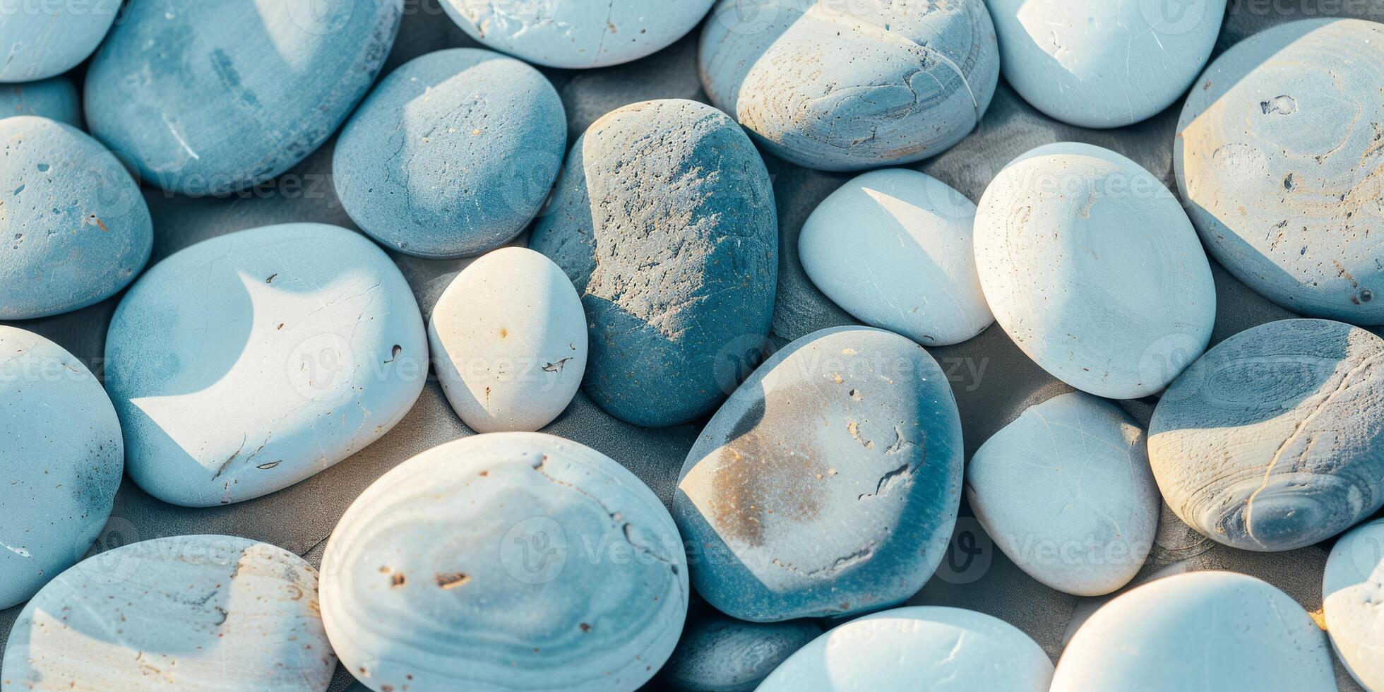 Collection of smooth, rounded blue stones and pebbles on beige sandy beach surface, natural texture background. photo