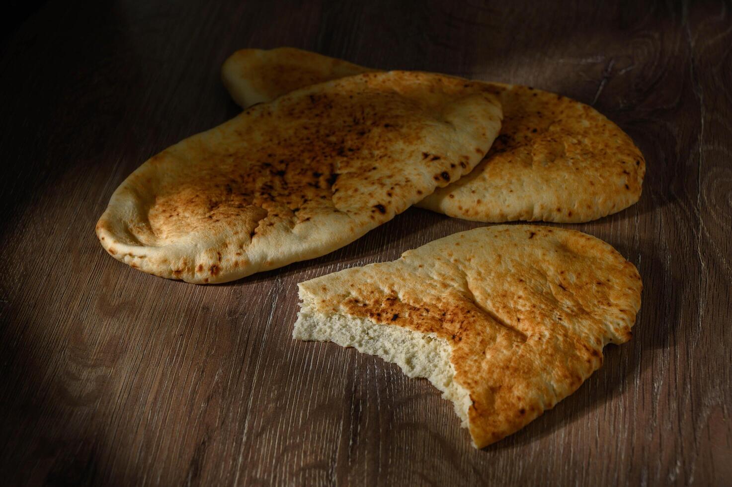 whole greek pita bread on wooden background photo