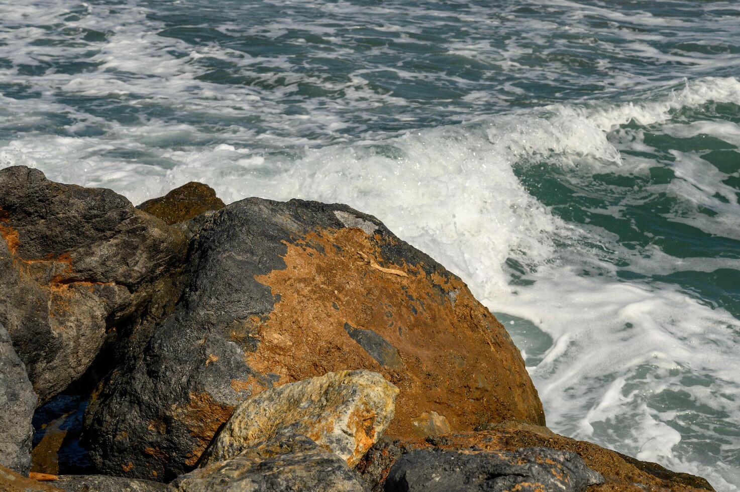 close up beautiful waves of the mediterranean sea breaking on rocks near the shore photo