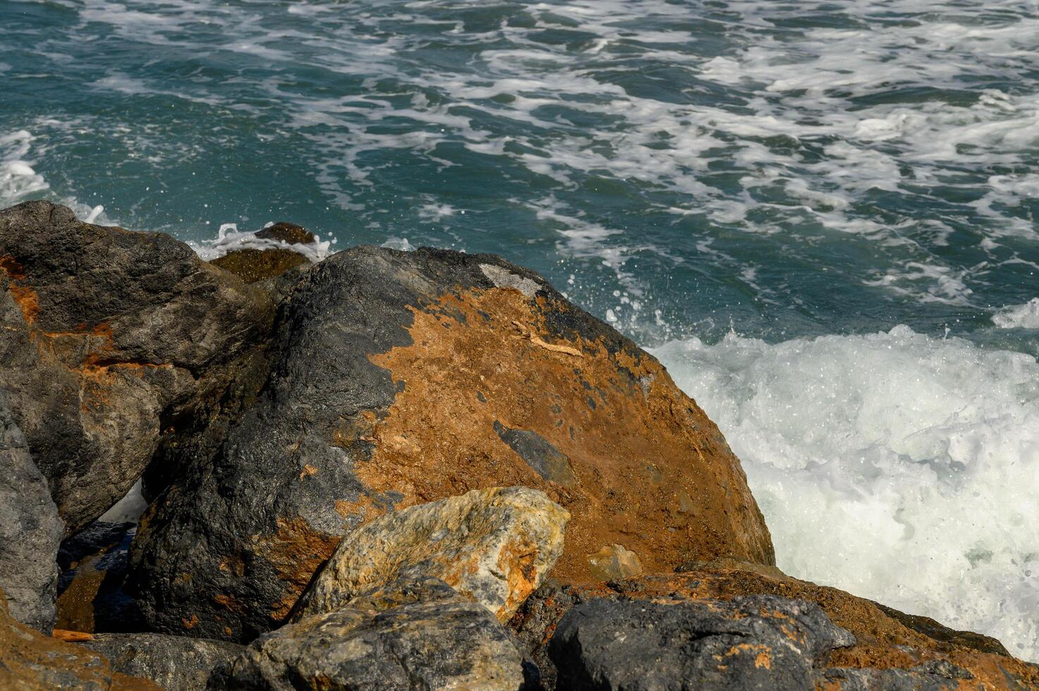 close up beautiful waves of the mediterranean sea breaking on rocks near the shore photo