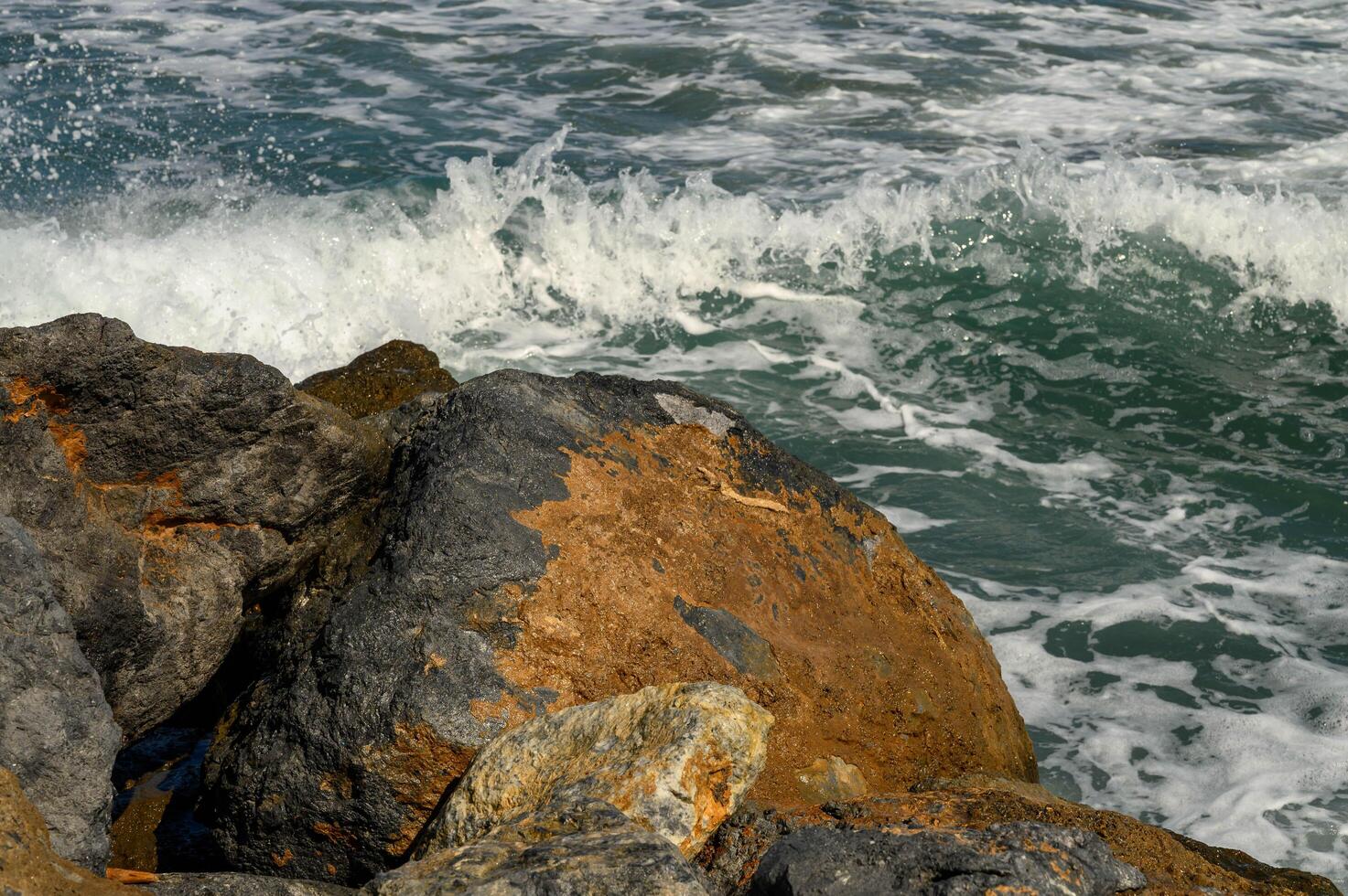 close up beautiful waves of the mediterranean sea breaking on rocks near the shore photo