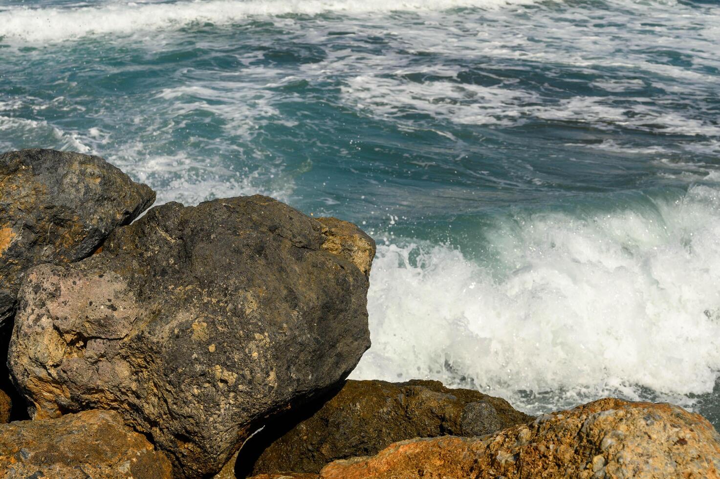 close-up of waves in the Mediterranean Sea crashing on rocks near the shore photo