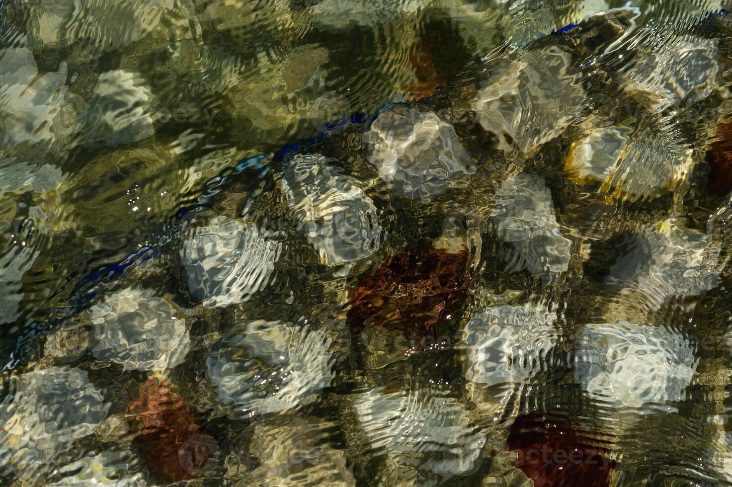 Rocky bottom of mountain river through the clear water photo