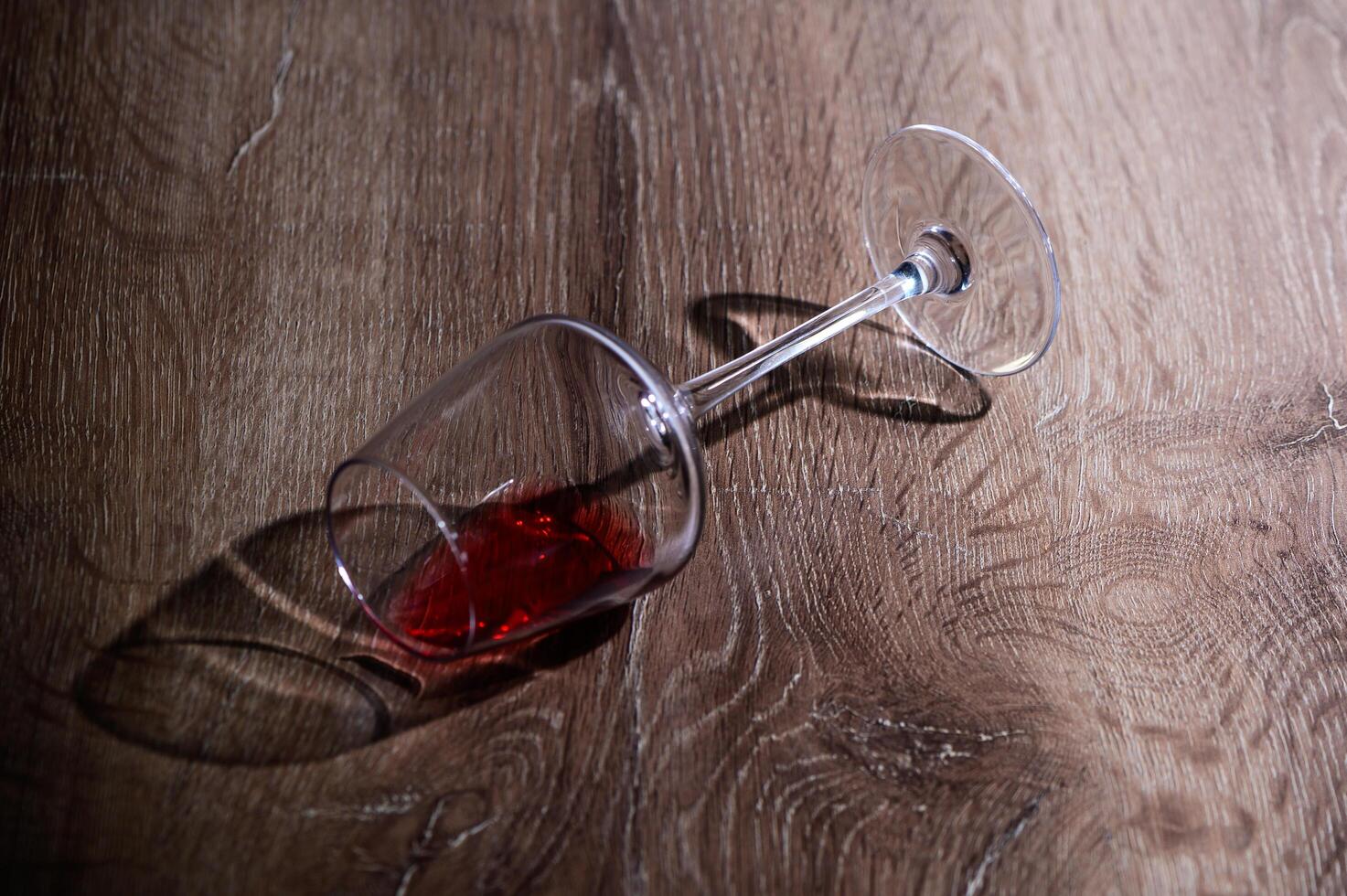 A glass of red wine lies on its side on the table. photo