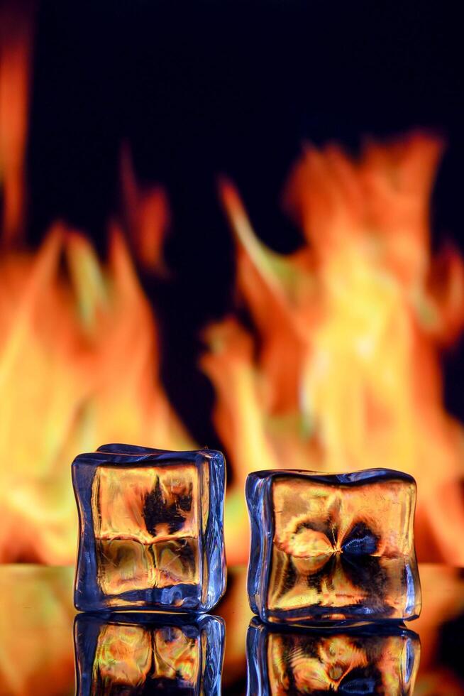 Conceptual photograph of an ice cube engulfed in flames, symbolizing the contrast between fire and ice. photo
