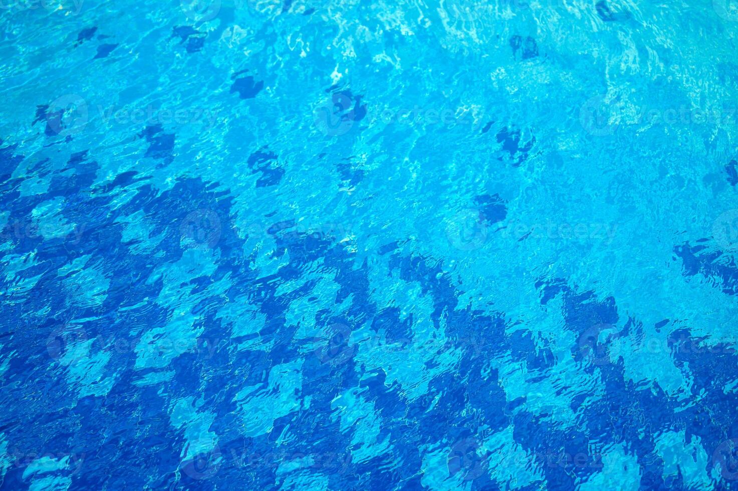 Blue water texture with light reflection. Water surface with rings and ripples, splashes and bubbles photo
