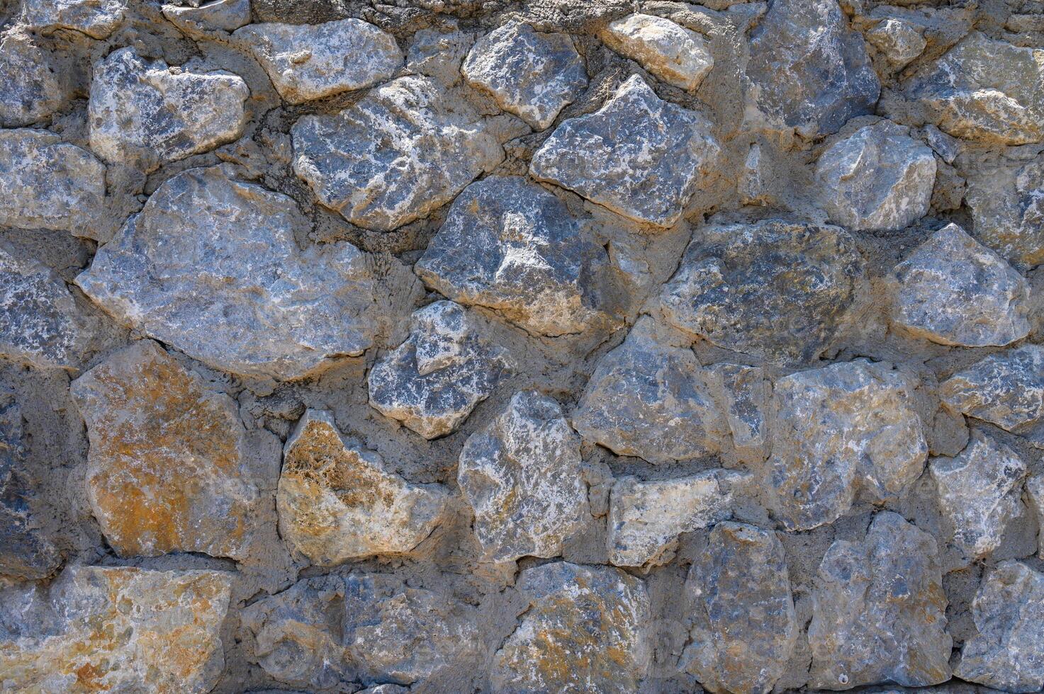 Grey stone wall with different sized stones, modern siding photo