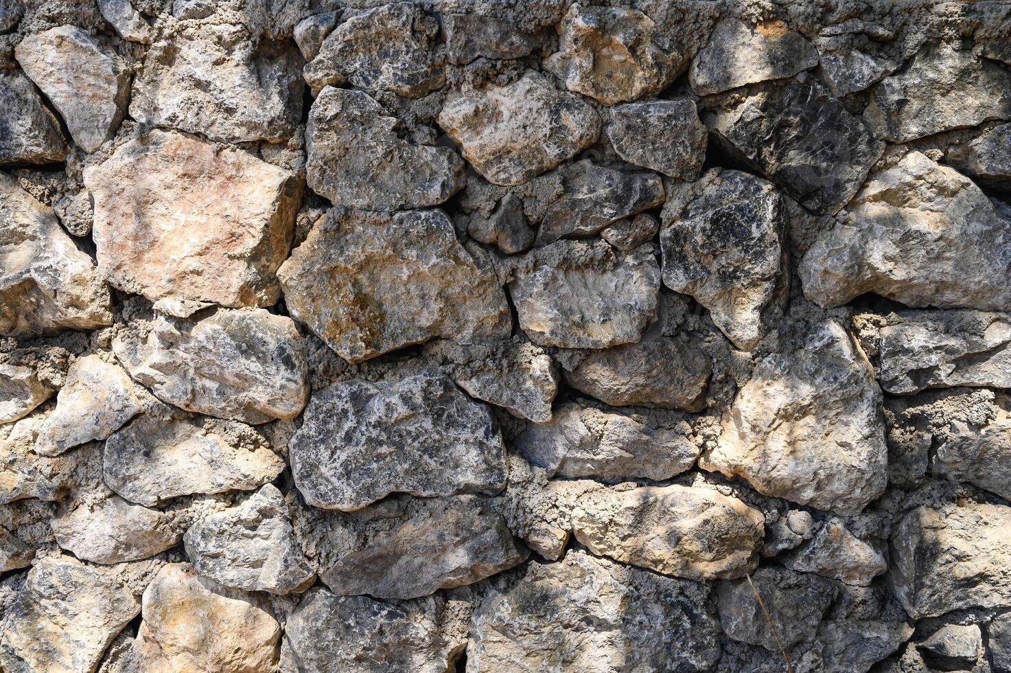 light and shadow on a wall made of real stone close-up texture photo