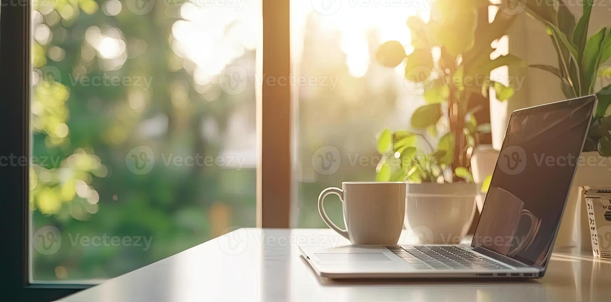 Blurred background of a modern home office interior with a laptop computer and a coffee cup on a white table, with copy space for text in the blurred window view. Business work from home concep photo