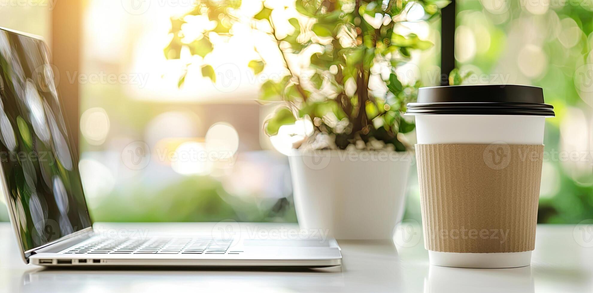 Blurred background of a modern home office interior with a laptop computer and a coffee cup on a white table, with copy space for text in the blurred window view. Business work from home concep photo