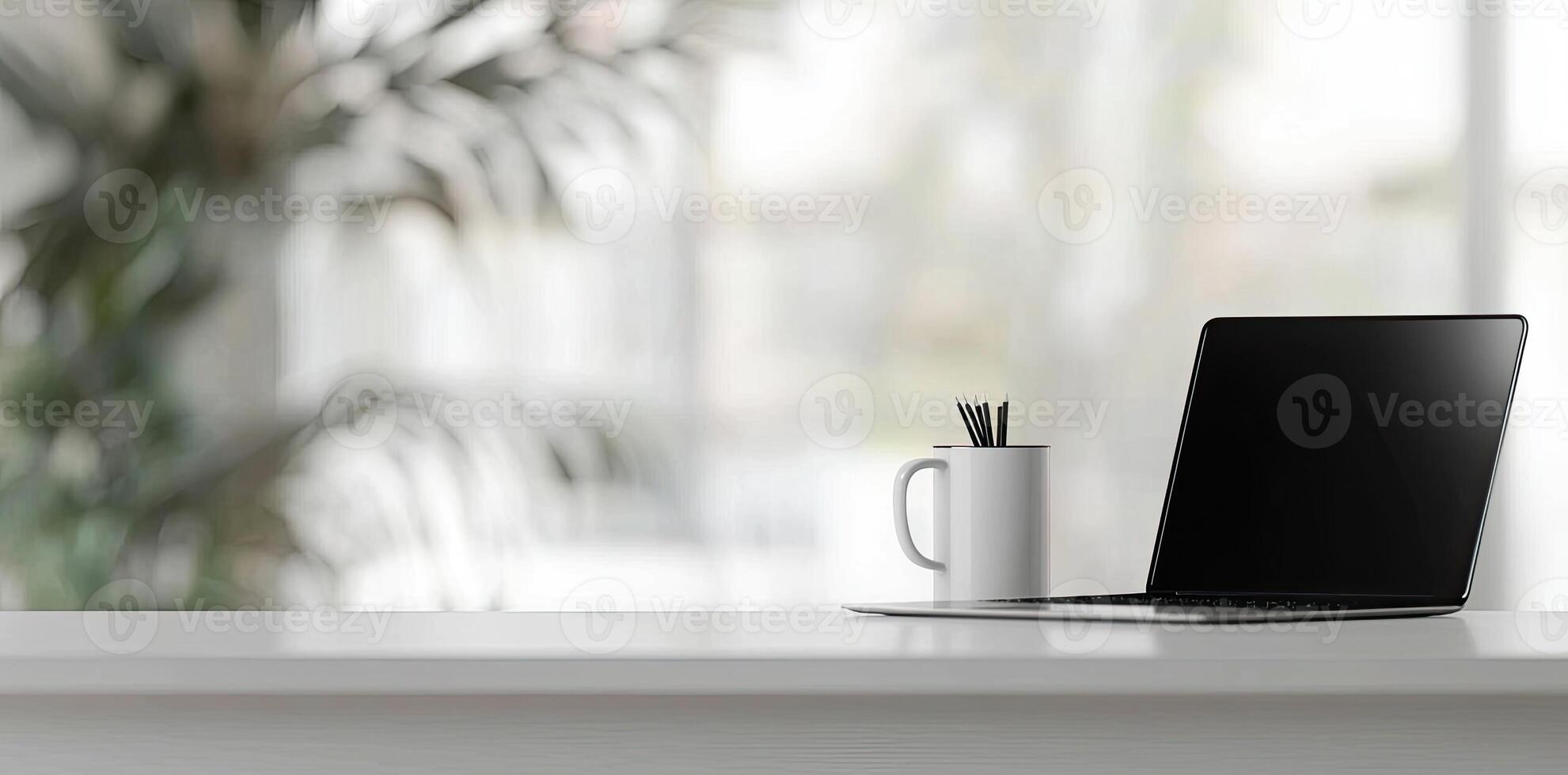 Minimalist white office desk with laptop and coffee mug on a blurred background, with space for text, representing the concept of working from home photo