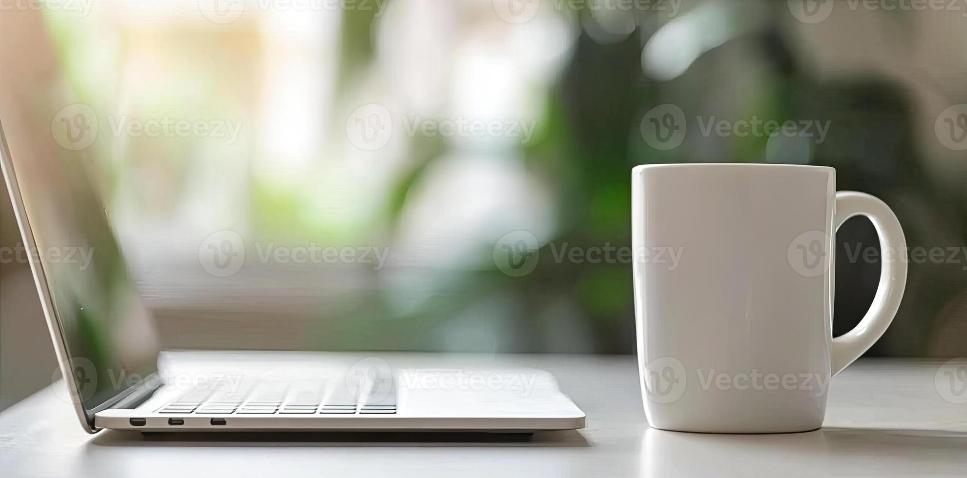 Minimalist white office desk with laptop and coffee mug on a blurred background, with space for text, representing the concept of working from home photo