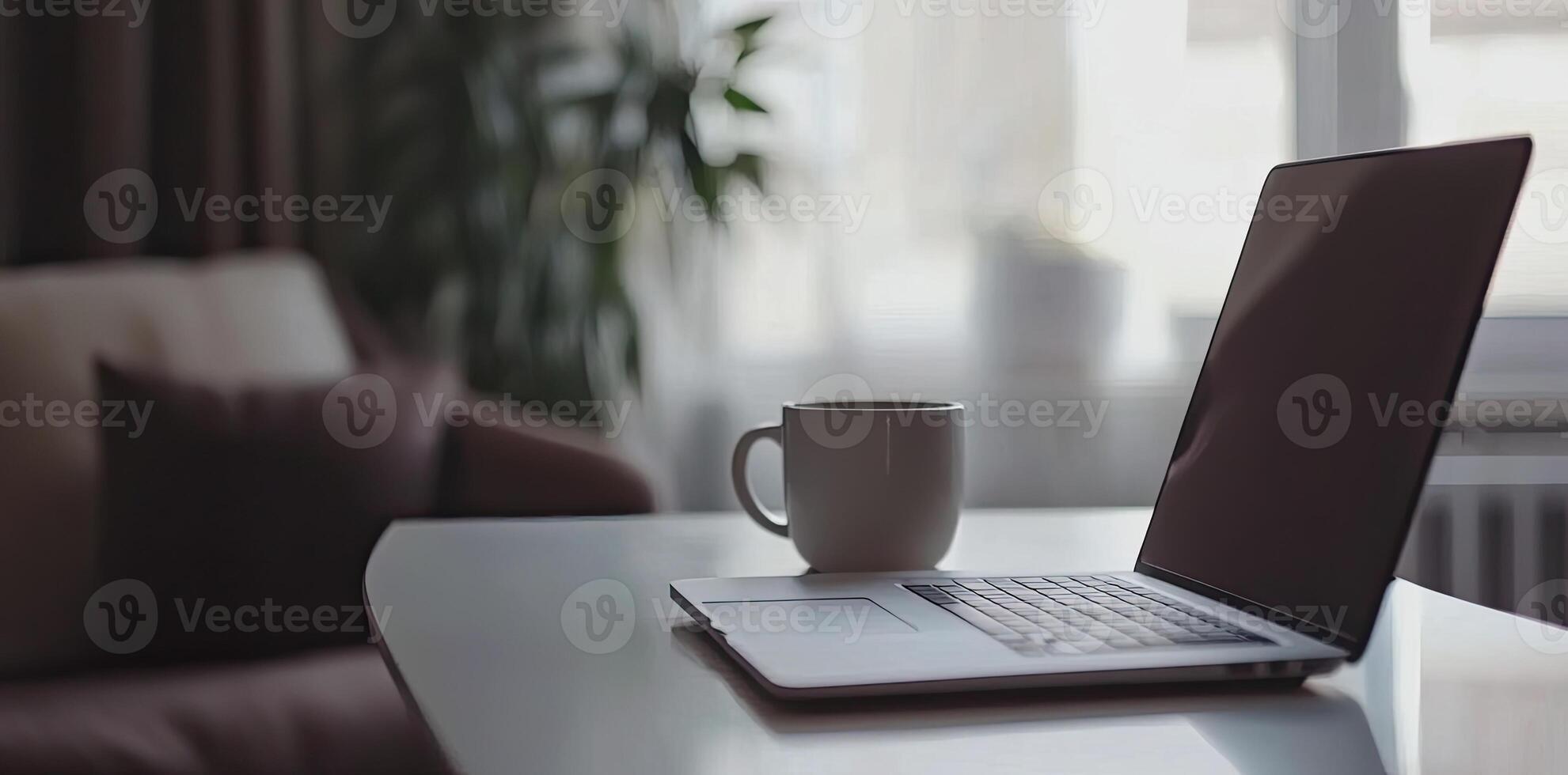 Minimalist white office desk with laptop and coffee mug on a blurred background, with space for text, representing the concept of working from home photo