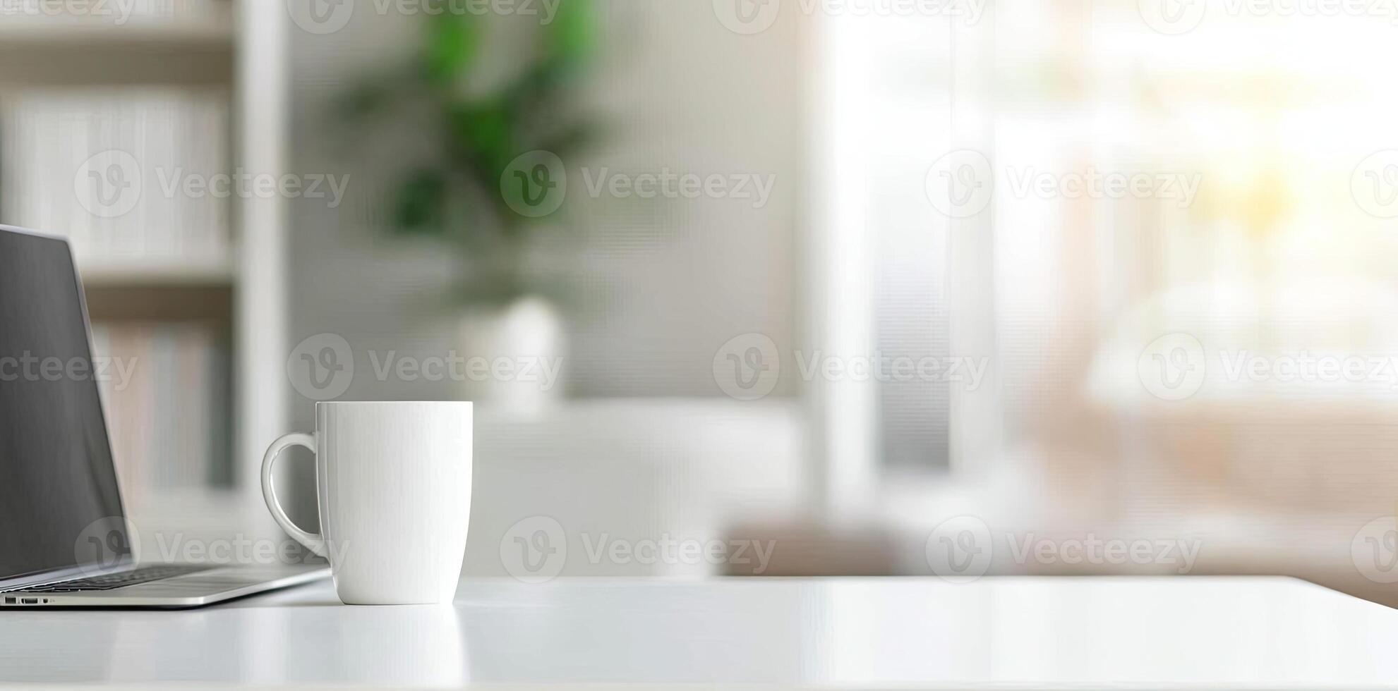 Minimalist white office desk with laptop and coffee mug on a blurred background, with space for text, representing the concept of working from home photo