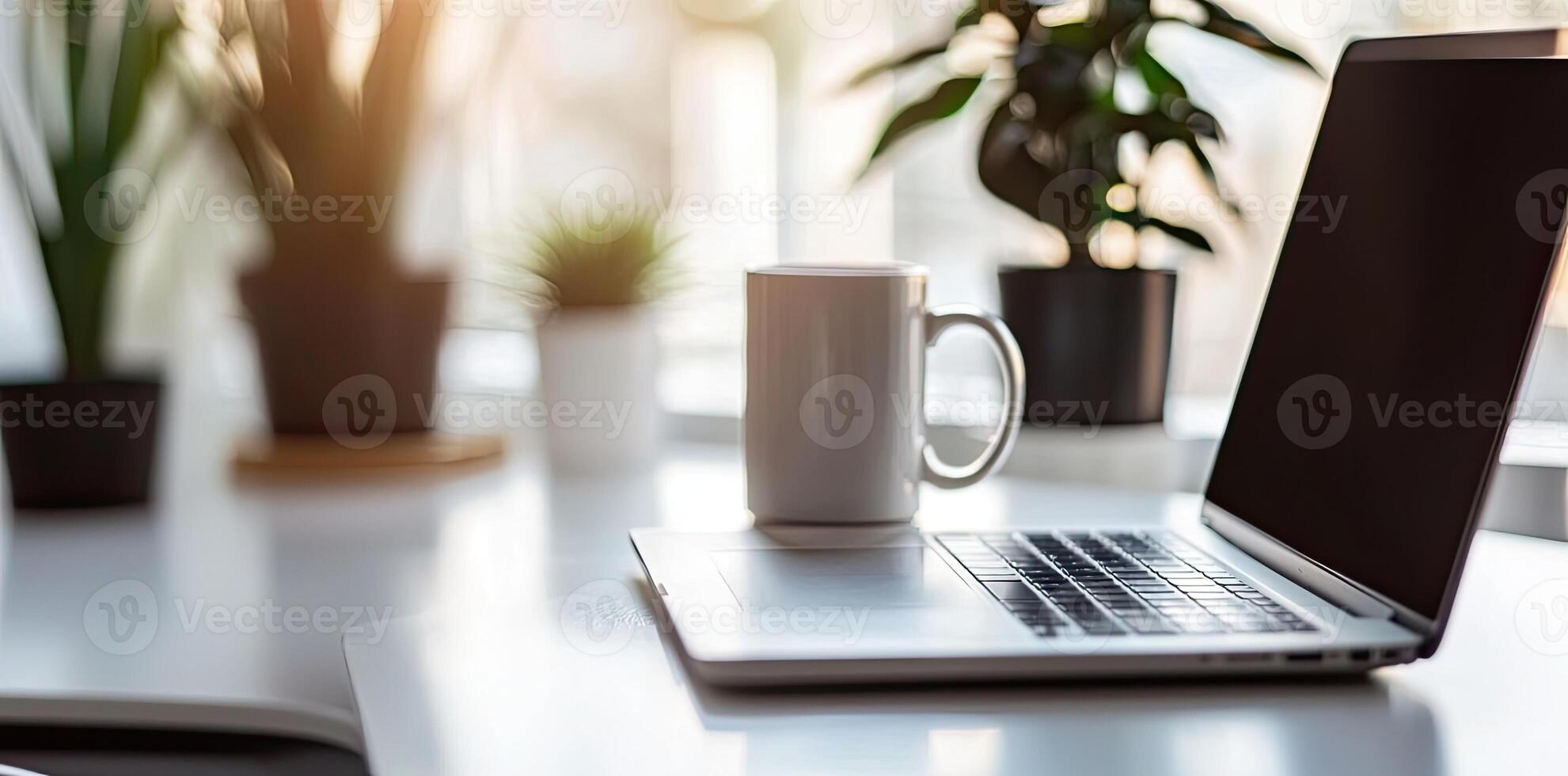 Minimalist white office desk with laptop and coffee mug on a blurred background, with space for text, representing the concept of working from home photo