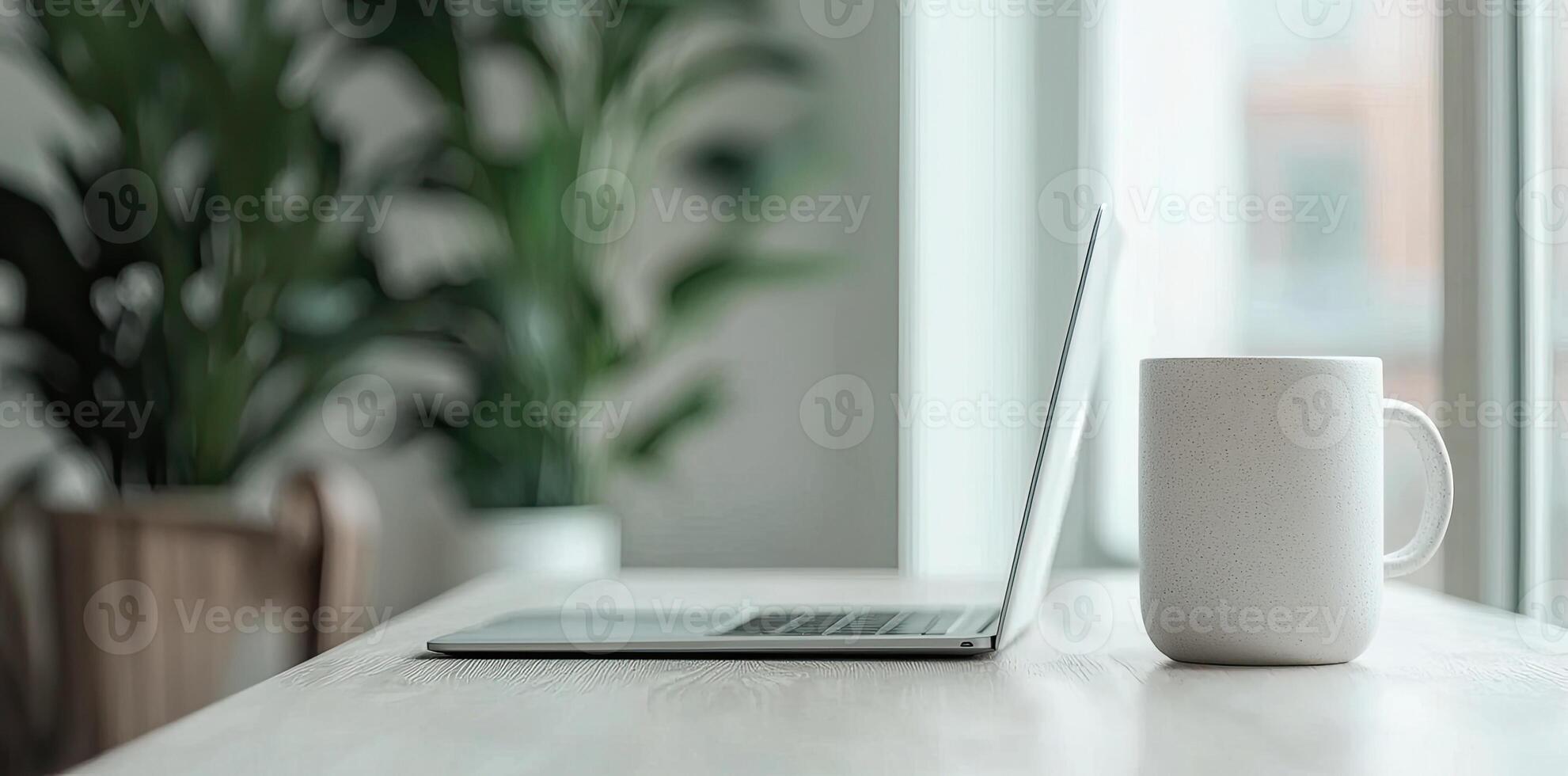 Minimalist white office desk with laptop and coffee mug on a blurred background, with space for text, representing the concept of working from home photo