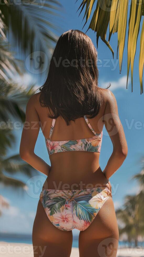 Model in a Beautiful Tropical Bikini Posing by the Glorious Sea. Enjoy a Serene Beach Day photo