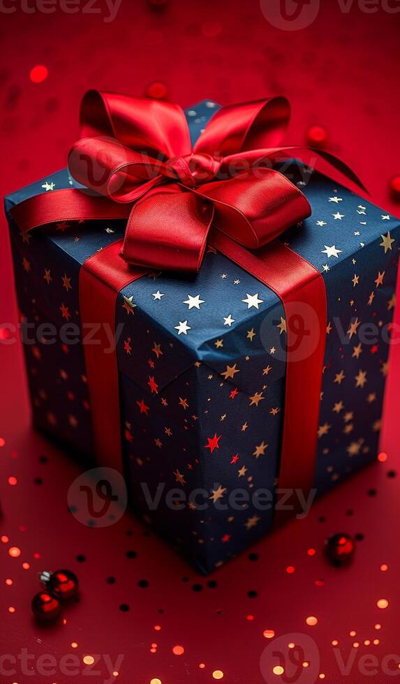 A blue box with a red bow on top of it. The box is decorated with stars and is sitting on a red background photo