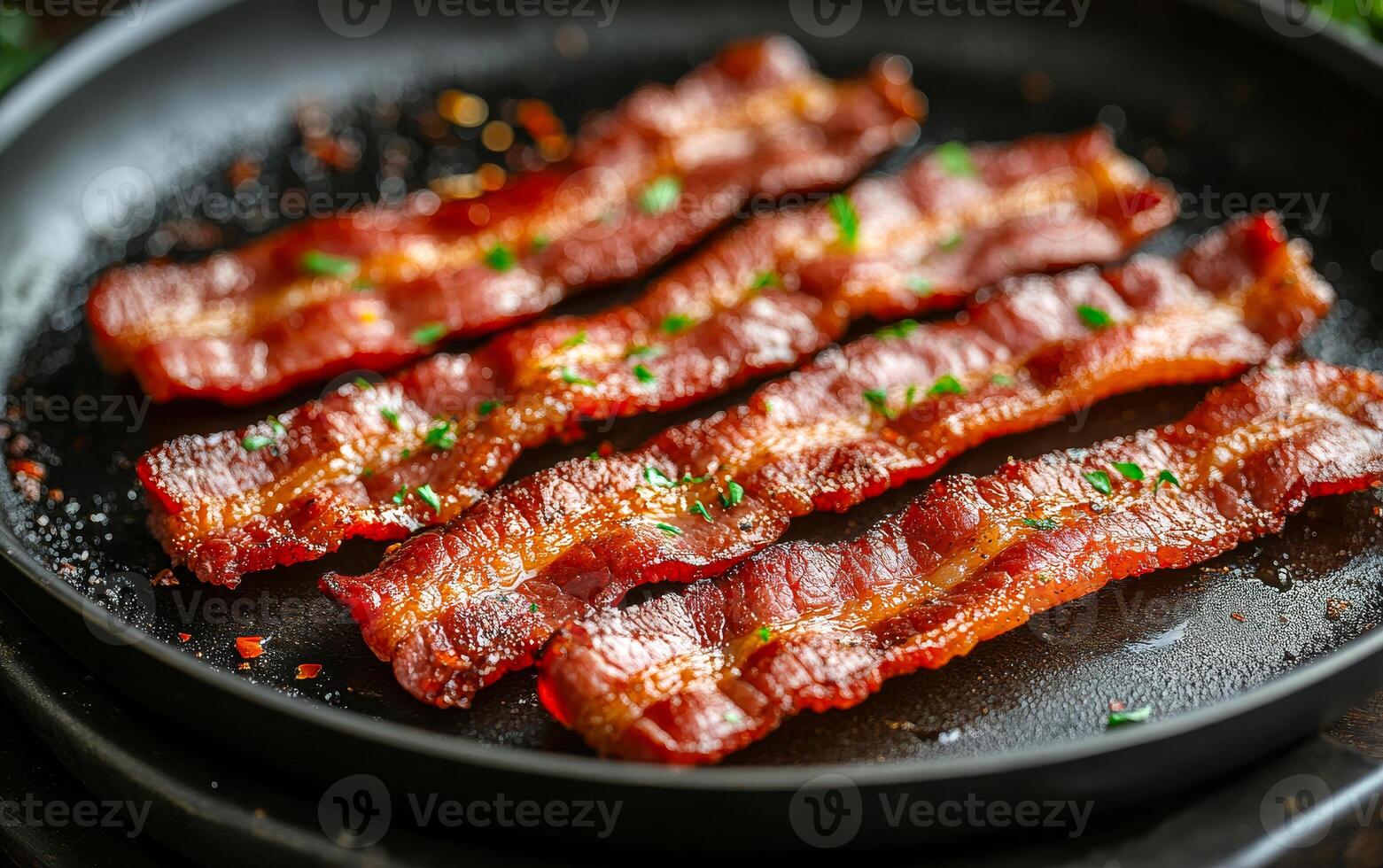A plate of bacon is on a black pan. The bacon is cooked and has a crispy texture photo