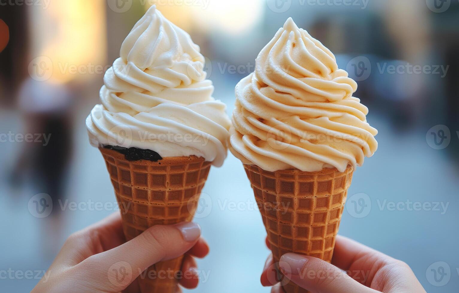 Two ice cream cones with whipped cream on top. One is white and the other is yellow. The person holding the cones is smiling photo